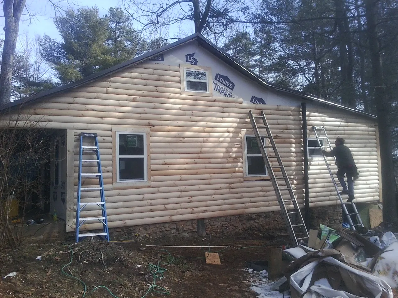 Ladders set against fresh log siding during an exterior remodel in Loughman