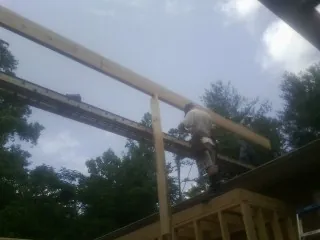 Carpenter setting a ridge beam over a new addition frame — Ice Dam Removal by Roofing Brothers in Loughman