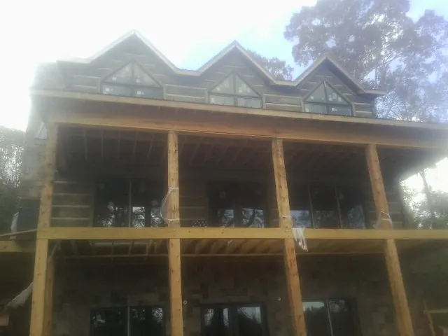 Dormers and porch framing on a large log home under construction — Roof Coating work by our crew in Loughman