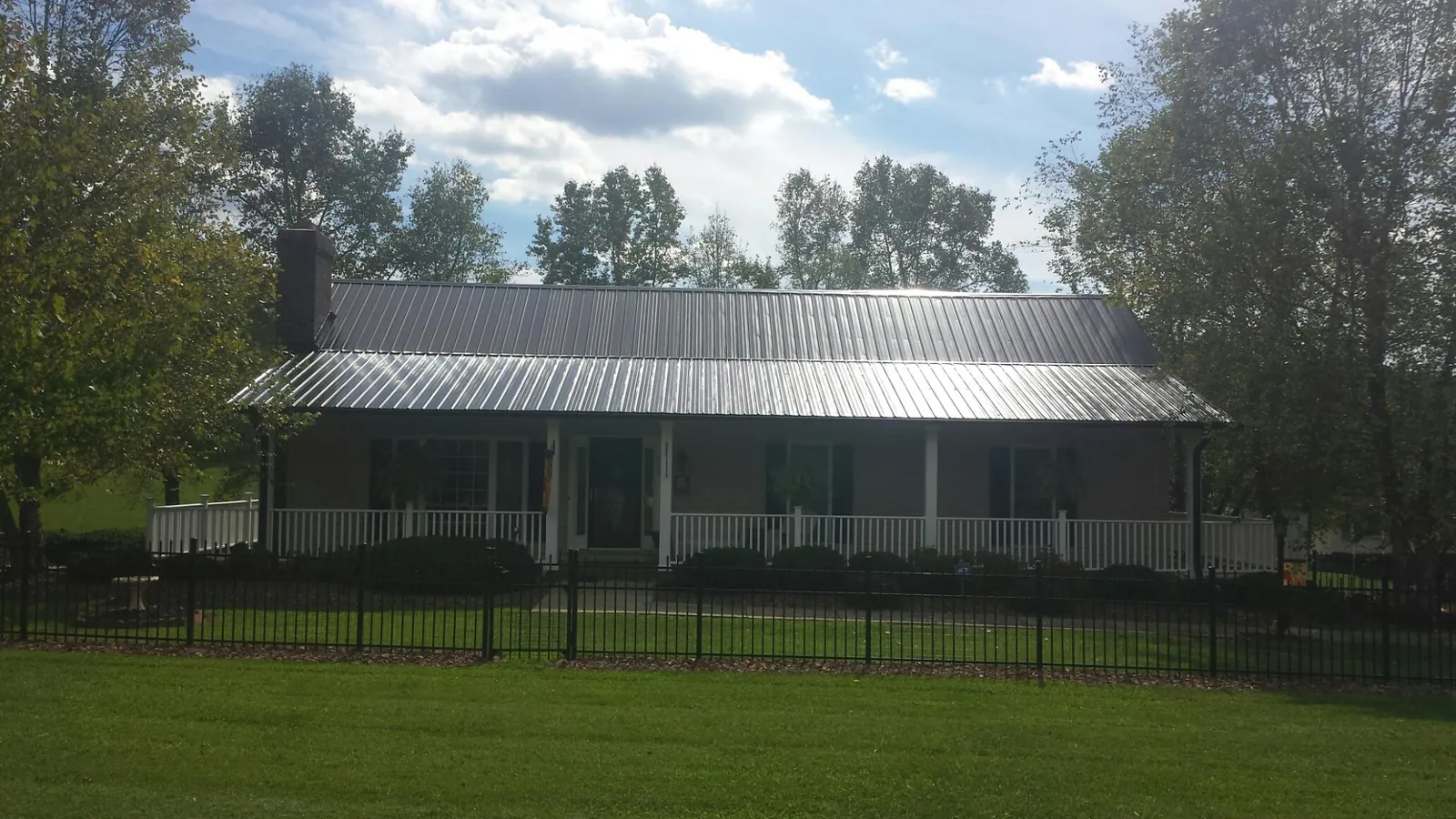 Gray metal roof on a brick ranch with a full width front porch — Gutter Guard Installation work by our crew in Loughman