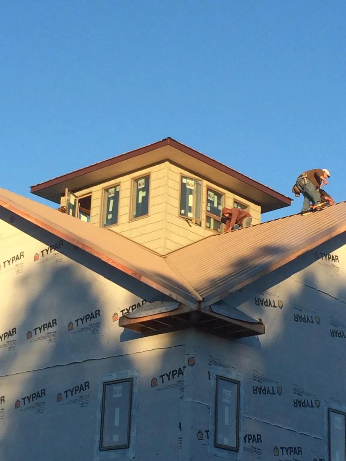 Roofers working around a rooftop cupola on a new metal roof at sunset — Roof Waterproofing in Loughman by Roofing Brothers